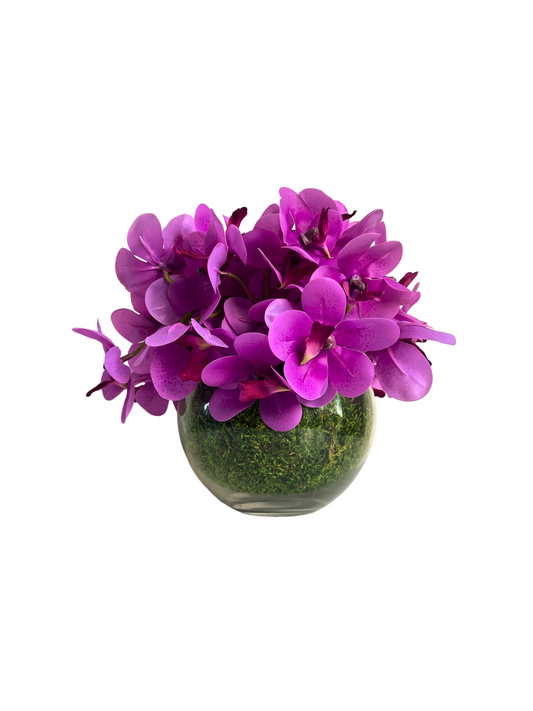 Artificial pink orchids set in a preserved moss lined glass ball vase.
