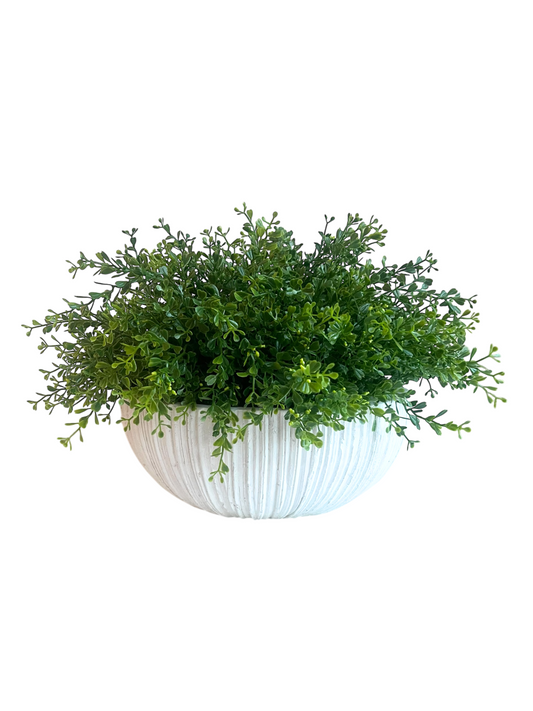 White ceramic ridged planter brimming with artificial lush green mini leaf plant.